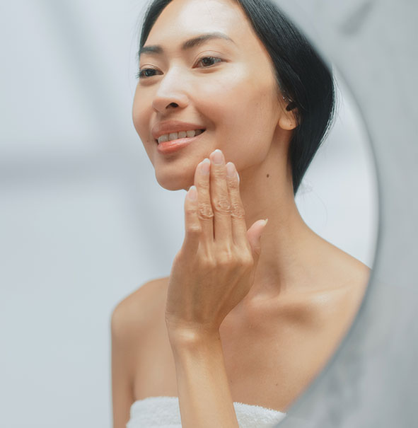Asian lady checking skin in mirror
